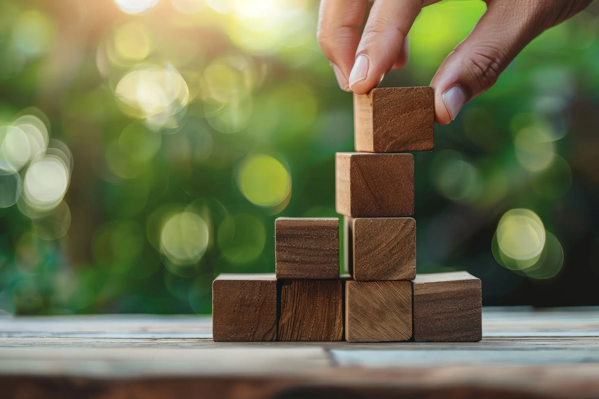 Close up of hand arranging wooden block into pyramid shape in business development and growth success process concept.