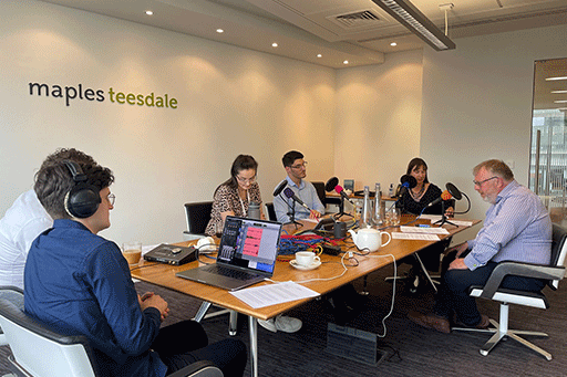5 people around a boardroom table recording a podcast