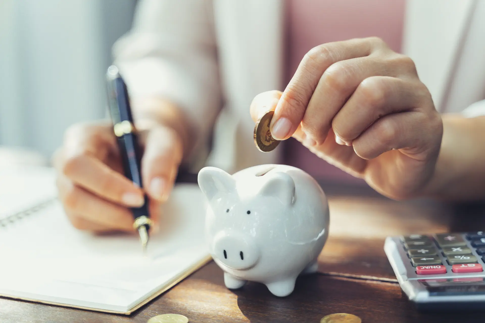 Closeup of business woman hand putting money coin into piggy bank for saving money.